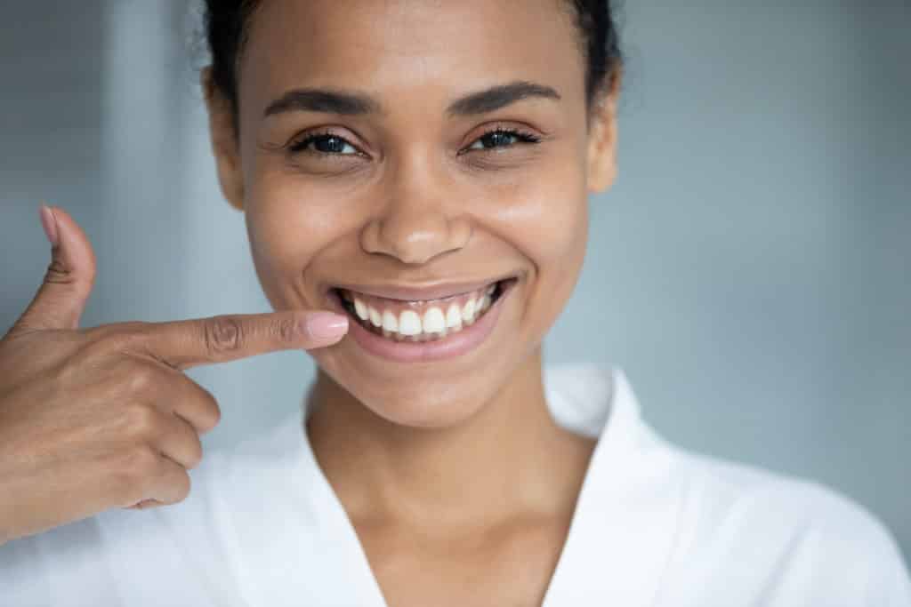 how to cover a cavity on front tooth- smiling dental patient pointing to white smile