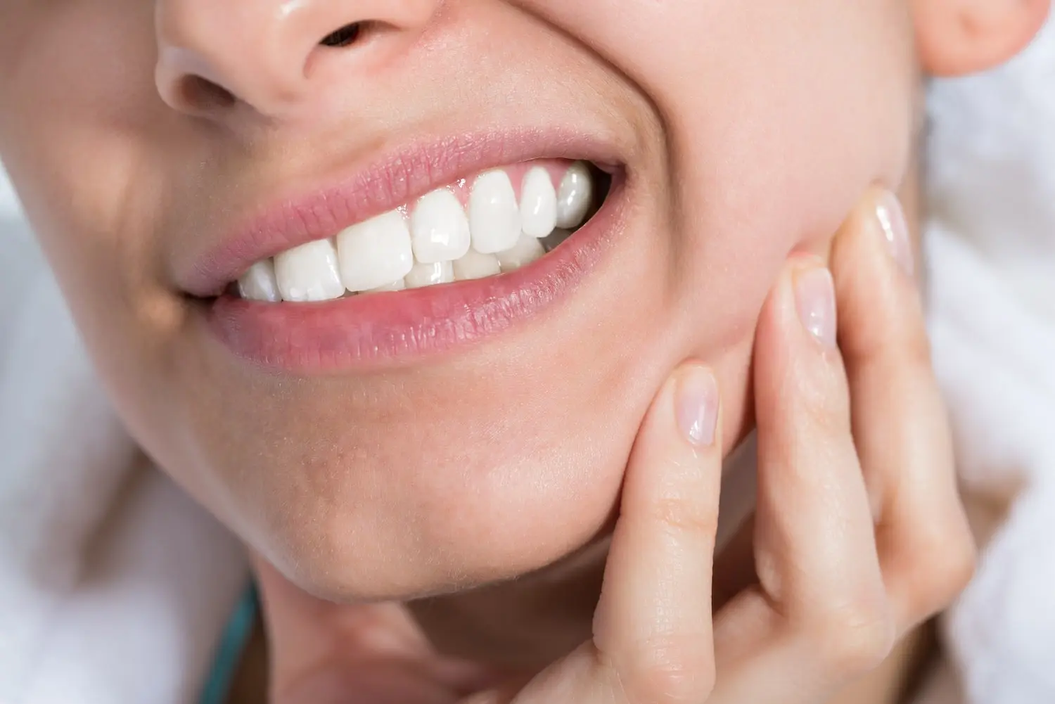 dry socket symptoms close up of woman's smile in pain holding cheek