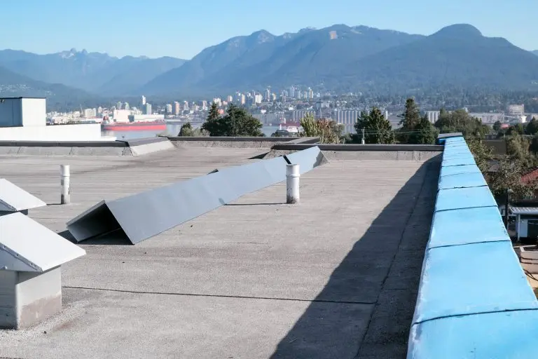 Roof metal flashing or coping installation. Roof repair with new waterproof membrane and sheet metal corners. Flat roof with modified bitumen roofing system with city and mountains. Selective focus.