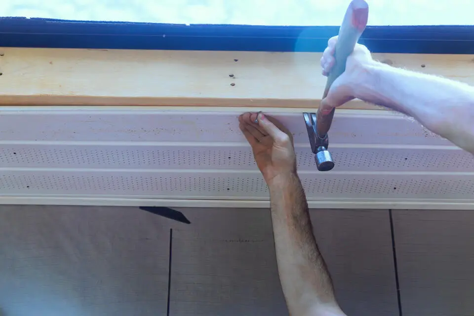 fascia board repair-man using hammer to repair fascia and soffit