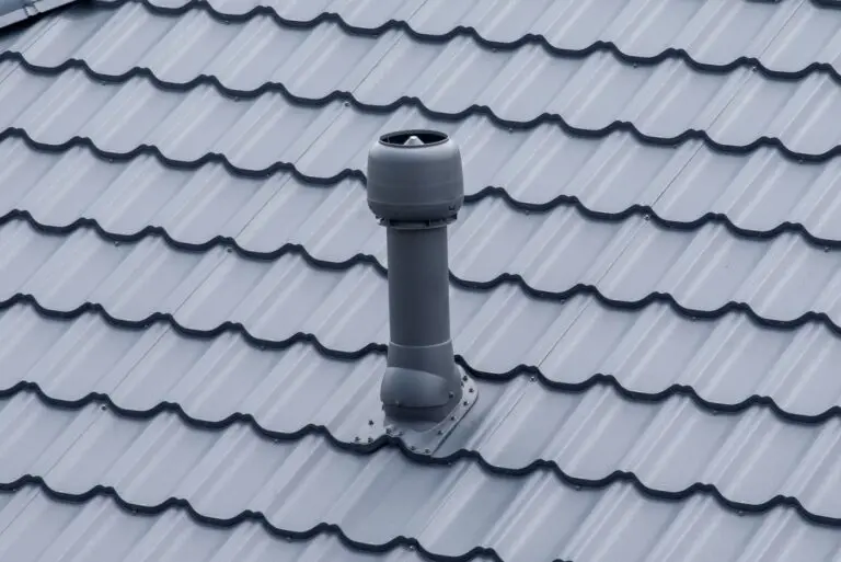 Plastic roof vent pipe on gray metal tile roofing