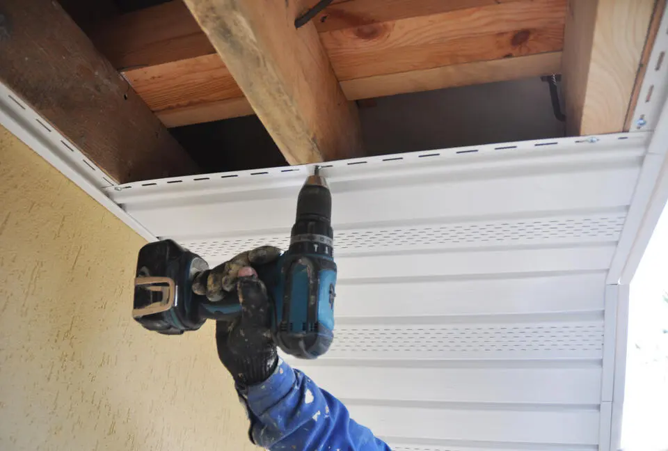 fascia board repair-close up man using power tool to install new fascia board