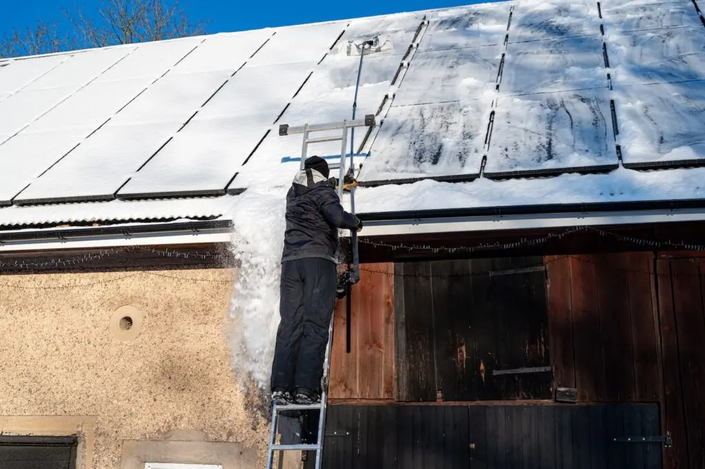 Man removing snow from solar panels on roof Kumla Sweden January 11 2025