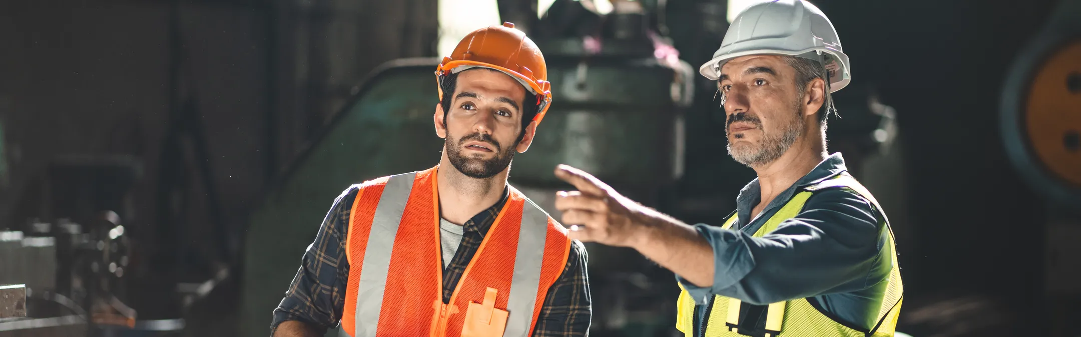 two construction workers discussing safety wearing hard hats and safety vests