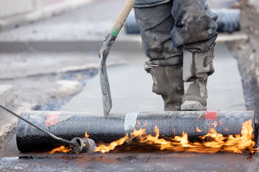 close up of commercial roofing contractor performing flat roof replacement with modified bitumen