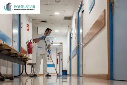Janitor cleaning hospital facility hallway with mop