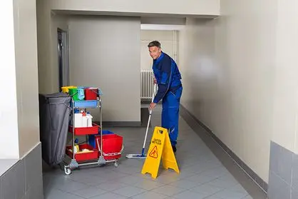 Full length of mature male worker with broom cleaning corridor