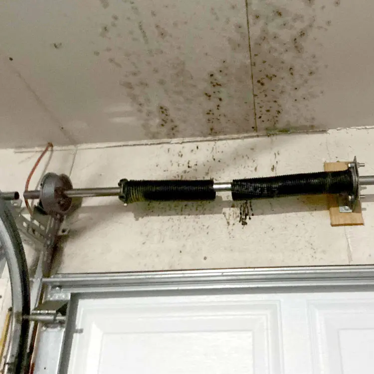Broken single garage door torsion spring before replacement in Everman, Texas.