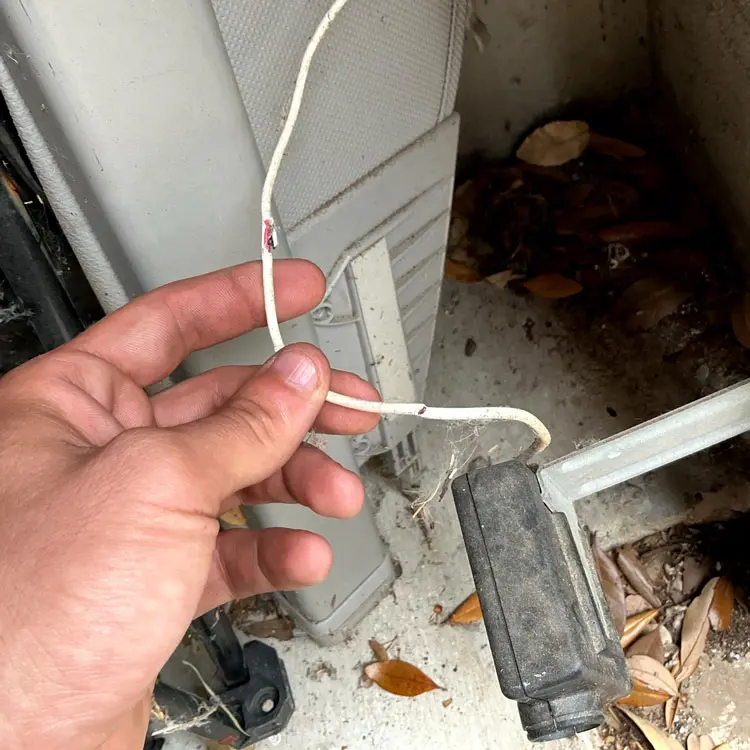 Worn garage door safety sensor wire before replacement in Austin, TX
