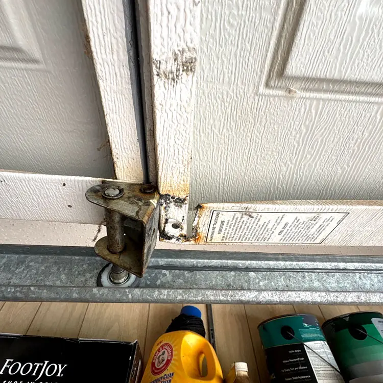 Torn garage door section around the bottom hinge and vertical stile before replacement in Oklahoma City, OK