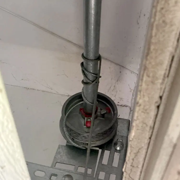 Snapped garage door lift cable beside the cable drum at a San Antonio, TX home