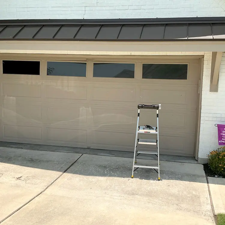 Aging raised-panel garage door with windows before replacement at an Austin, TX home