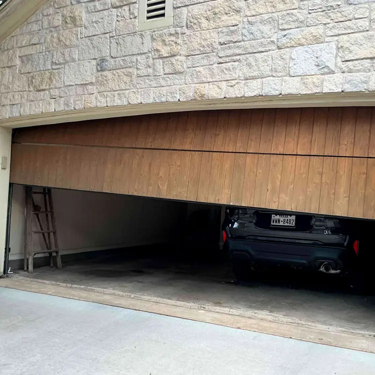 Wood-look garage door sitting crooked and partially open after coming off its track in Austin, TX