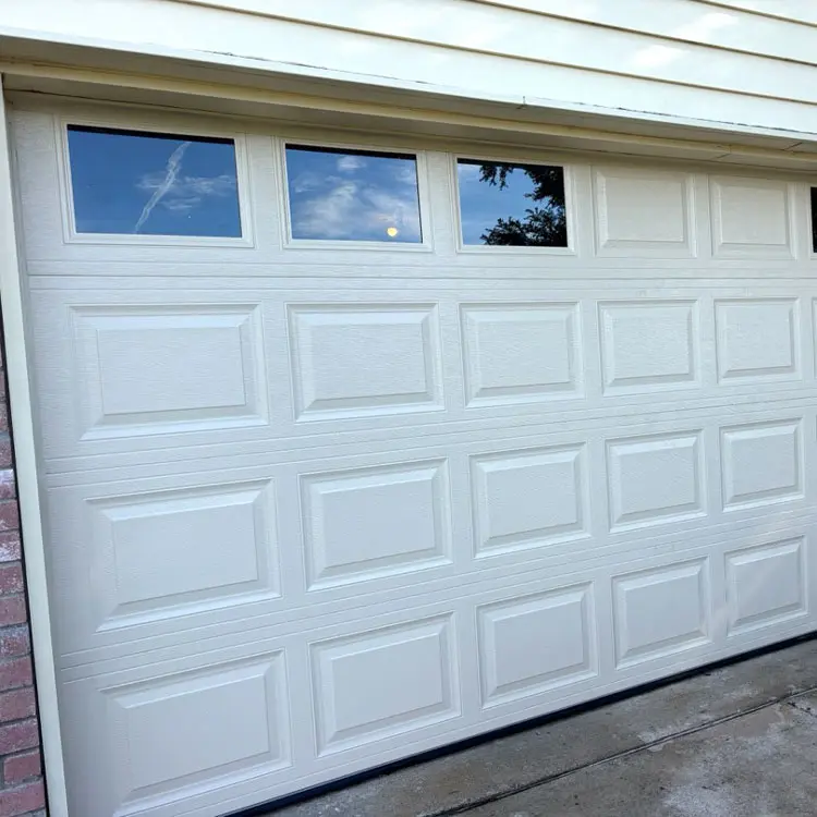 Existing white raised-panel garage door with windows before replacement at a Tulsa, OK home