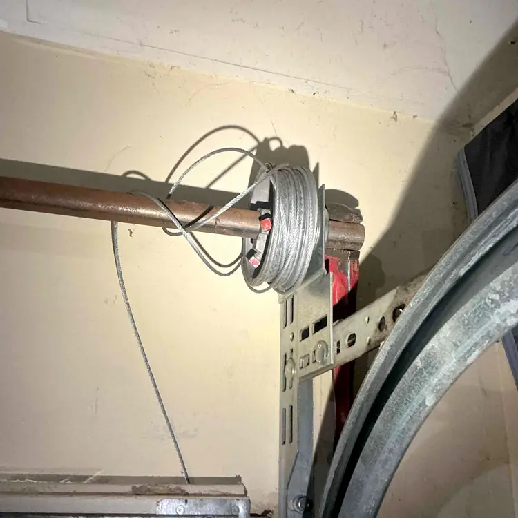 Tangled garage door cable off the drum before repair in Houston, TX
