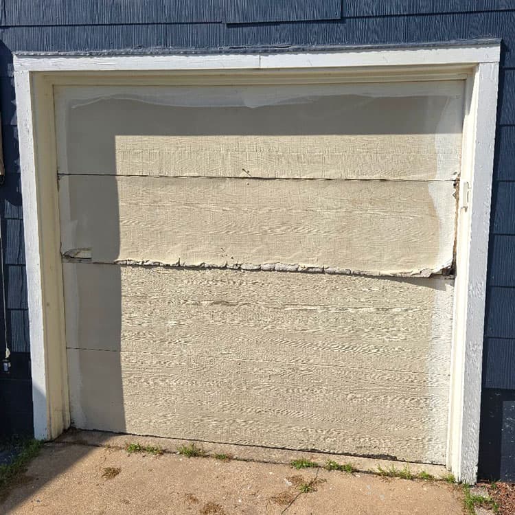 Peeling and deteriorated wood garage door before replacement at a Tulsa, OK home