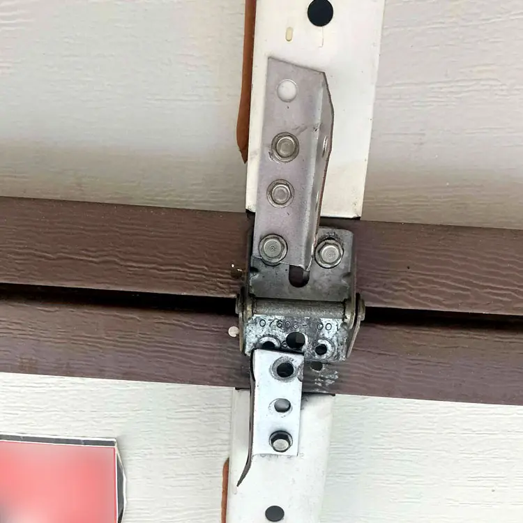 Improvised garage door hinge before proper hinge replacement in Houston, TX