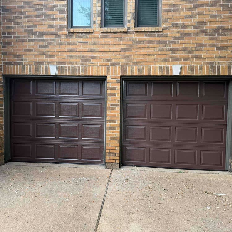 Two matching dark brown raised-panel garage doors installed in Houston, TX