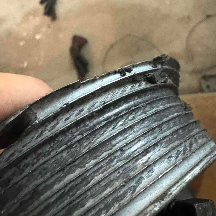 Close-up of a damaged garage door cable drum with heavily worn grooves in Tulsa, OK