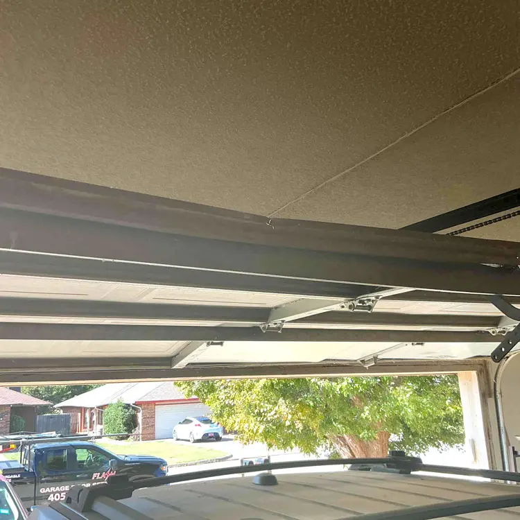 Interior view of cracked and damaged garage door panels before replacement in Oklahoma City, OK
