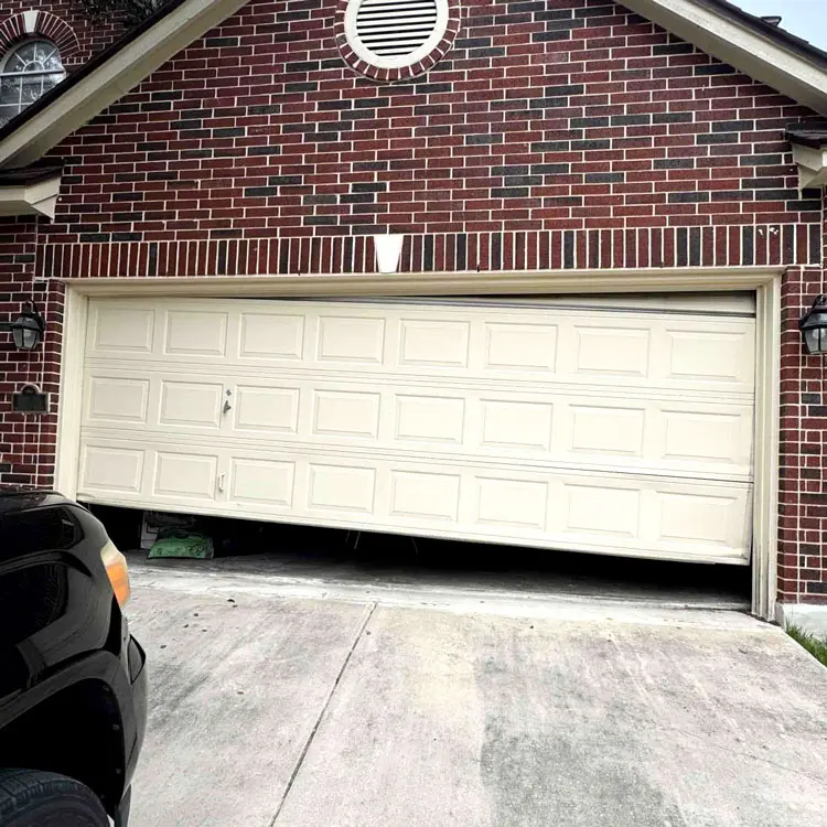 Crooked garage door hanging unevenly after coming off track at a San Antonio, TX home