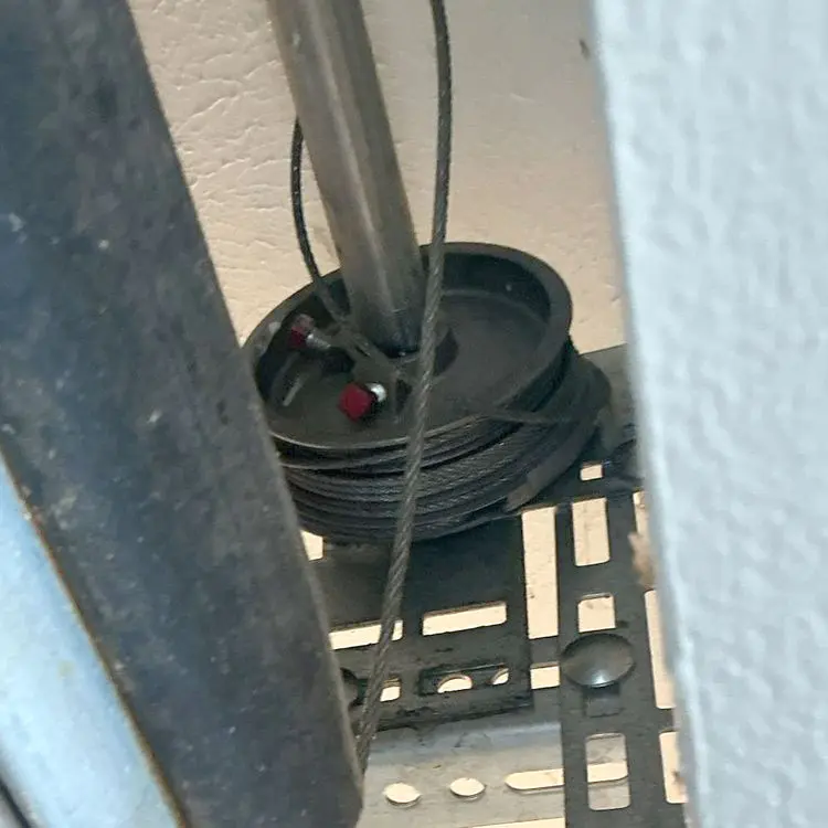 Garage door cable repair in Dallas, TX with new lift cables, premium rollers, and a replacement bottom bracket installed.