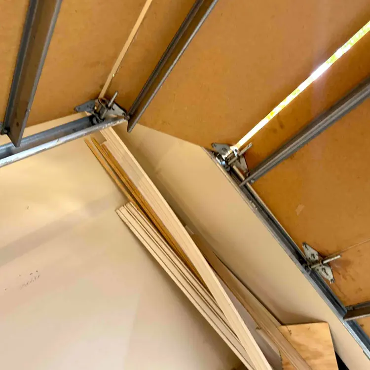 Metal reinforcement struts installed across an aging wood garage door in Tulsa, OK