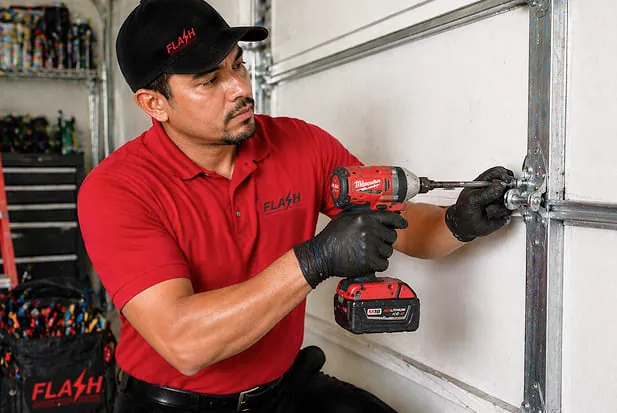 garage door technician repairing and adjusting hinges on a residential garage door to ensure smooth and safe operation.