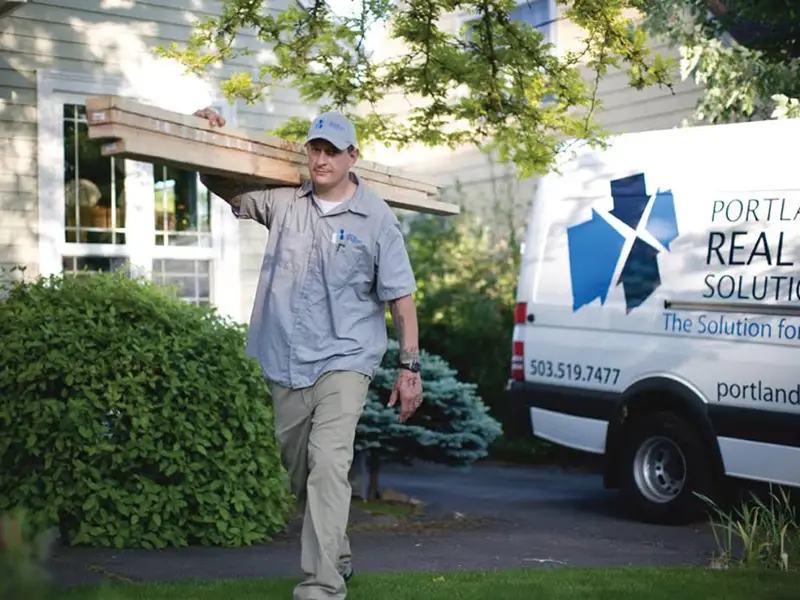 Portland Construction & Restoration crew member carrying lumber on a job site