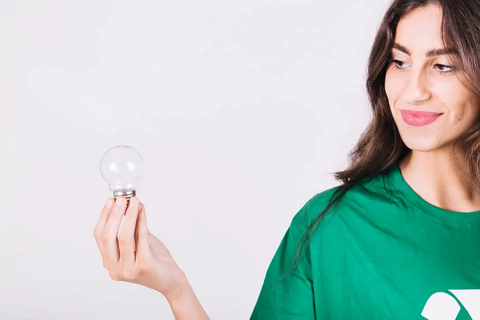 A woman holding a lightbulb on a white background.