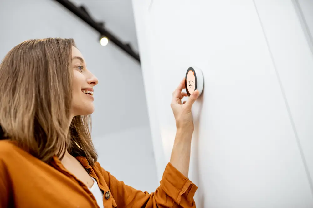 Embrace the Future of Home Comfort: A Comprehensive Guide to Programmable Thermostats - Woman adjusting a re-programmable thermostat
