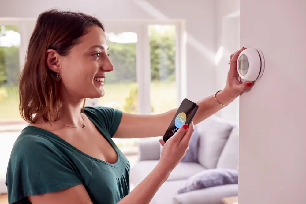 Woman using her phone app to control programmable thermostat