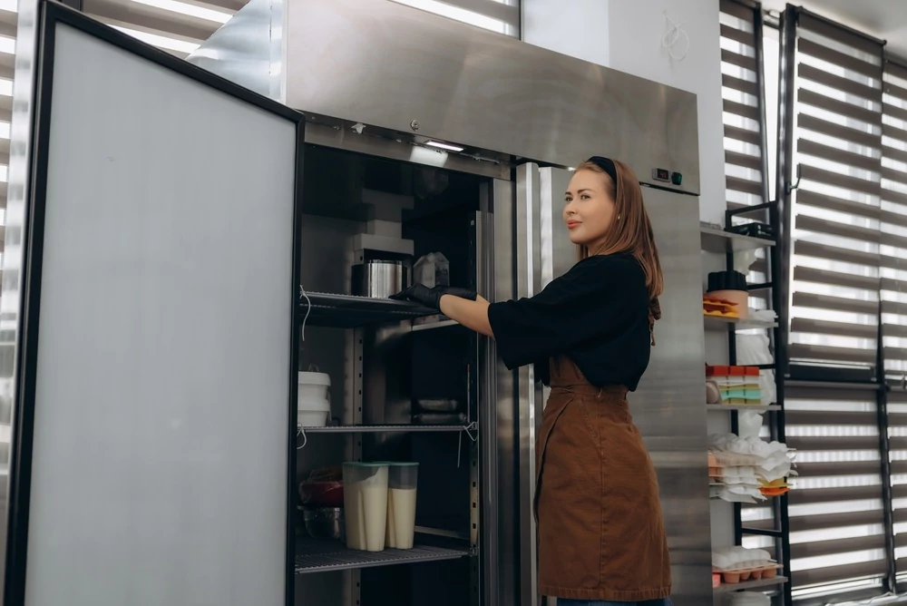 Female chef storing ingredients in commercial fridge