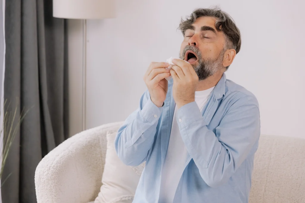 Senior man sneezing into a tissue