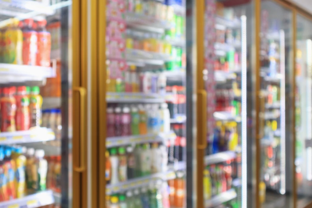 Supermarket convenience store refrigerators with soft drink bottles on shelves abstract blur background