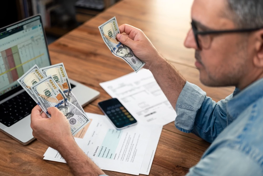 middle aged man looking at money and utility bills