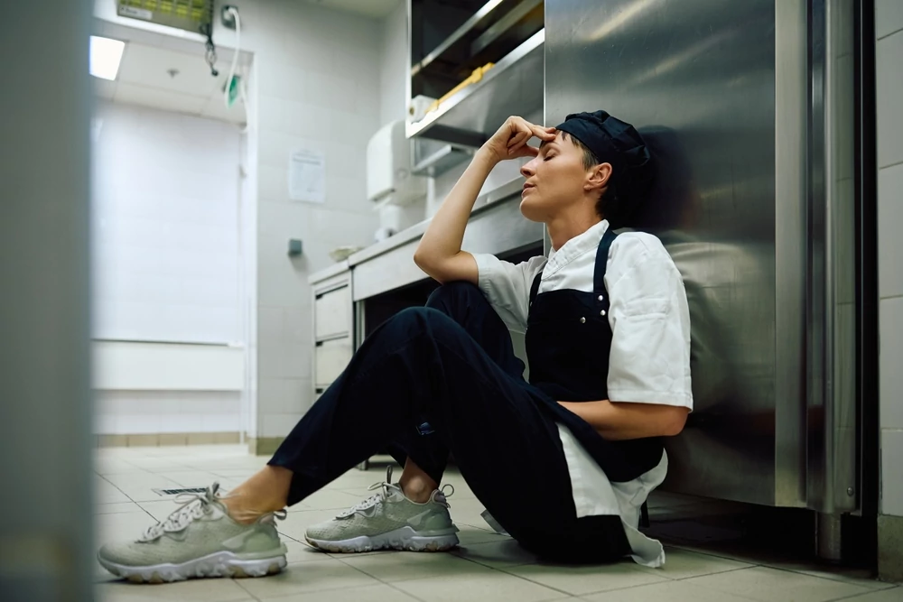 stressed female cook sitting on the floor