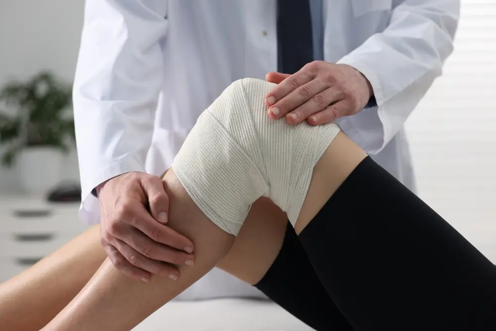 Un profesional médico examina la rodilla de un paciente envuelta en un vendaje durante una sesión abierta de resonancia magnética por dolor de espalda en Brooklyn, Nueva York.