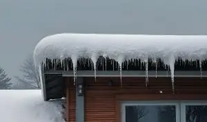Roof covered in a thick layer of snow, with icicles hanging from the edge in Denver, CO.