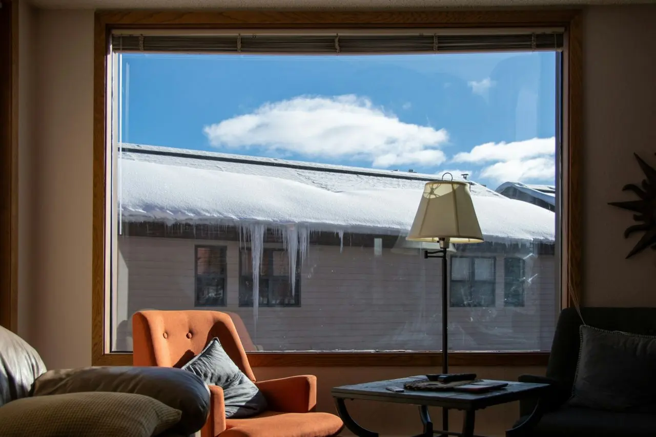 Roof with icicles seen through the window of a cozy living room