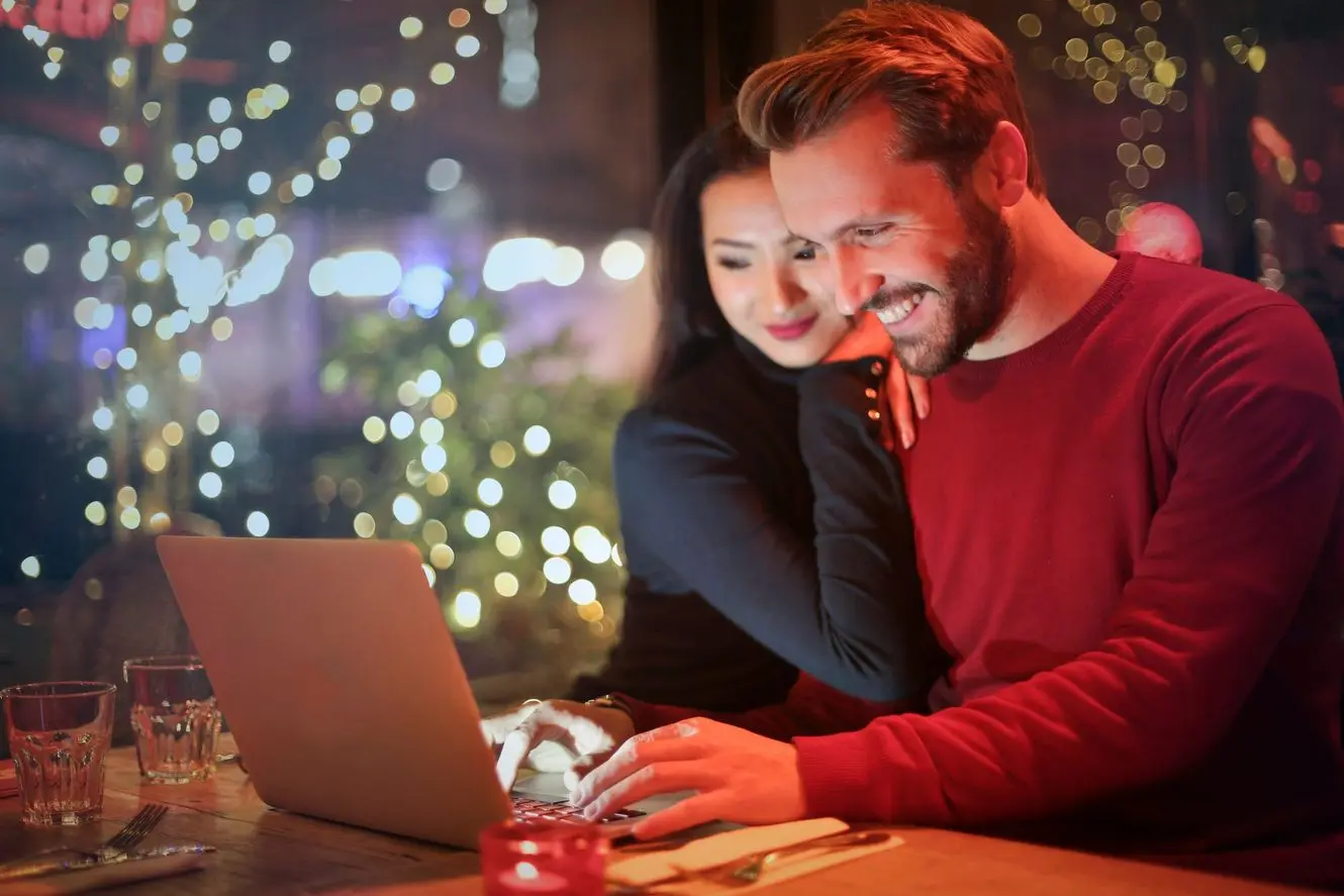 Couple sitting at a table and researching apartment roofing insights for new tenants on a laptop.