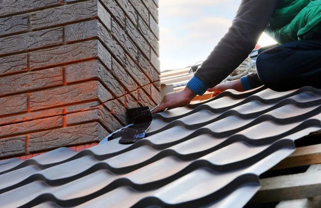 worker installing dark grey metallic tiles