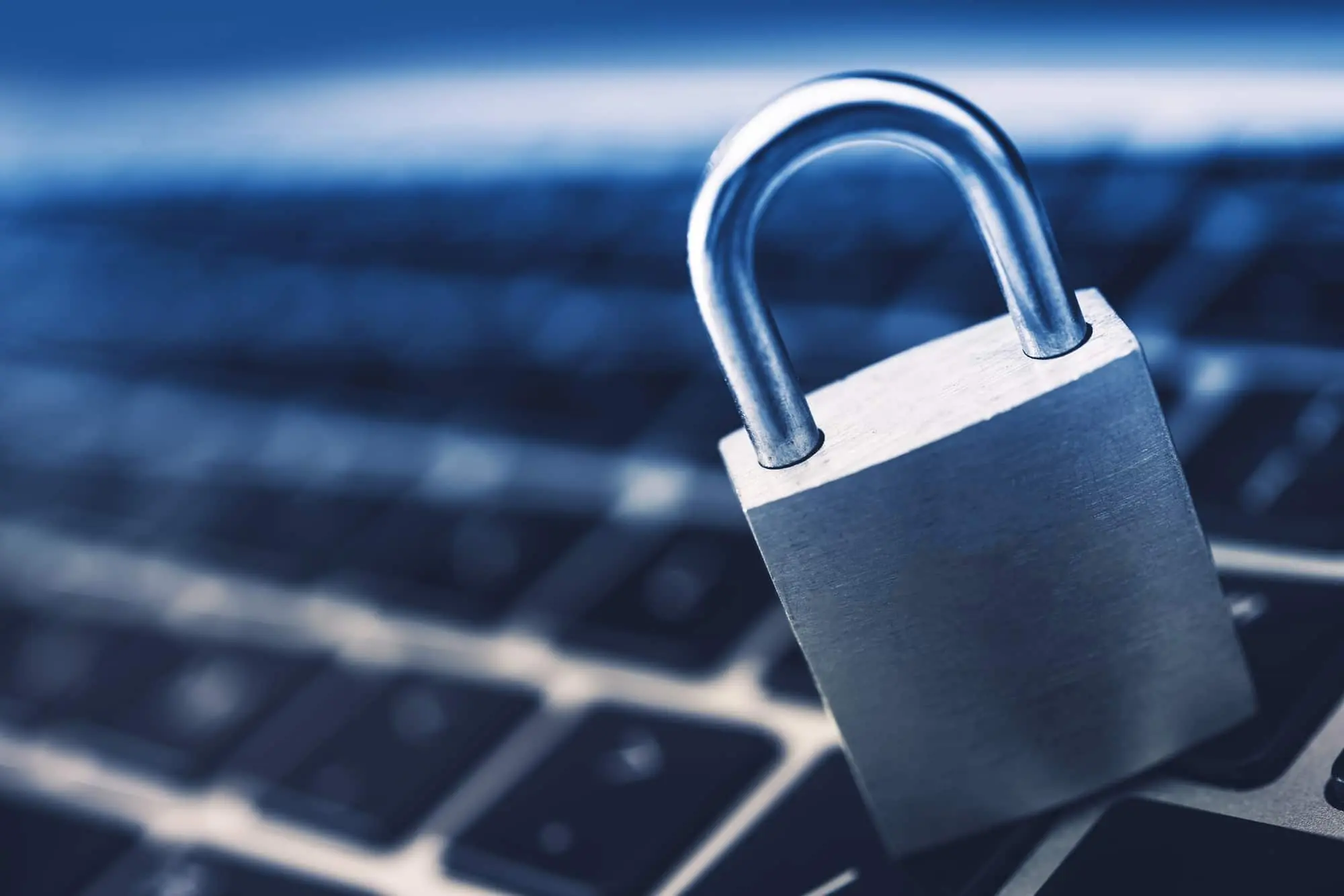 A steel padlock resting on a laptop keyboard.