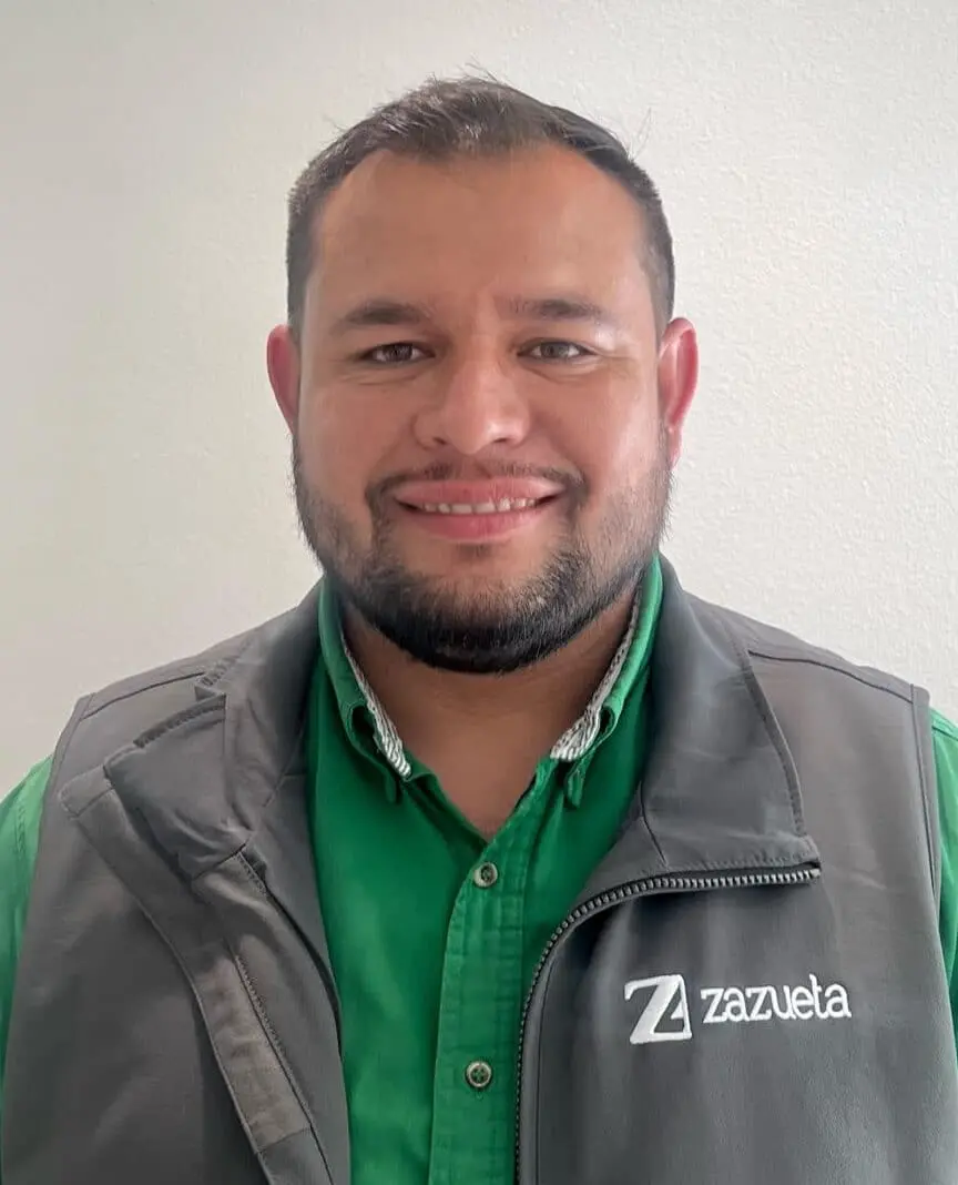 Zazueta Tree Specialists Team Member - Zazueta Tree Specialists - Zazueta Tree Specialists : Jesus, a Zazueta Tree Specialists team member, smiling while wearing a green shirt and gray branded vest.