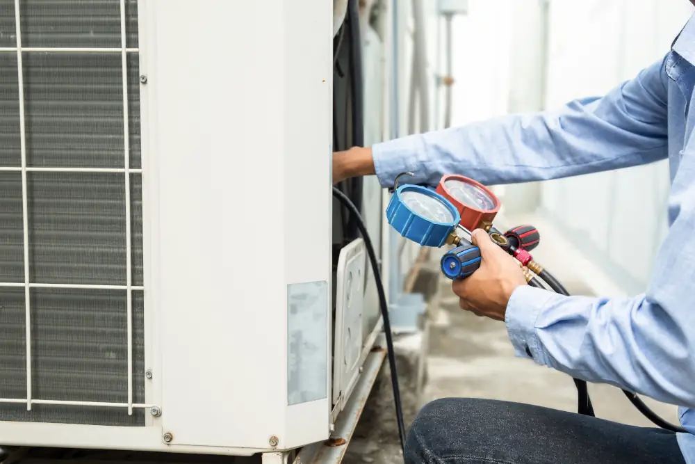 The Importance of Regular AC Maintenance to Prevent Costly Repairs - HVAC technician using equipment on HVAC unit ot measure freon levels.