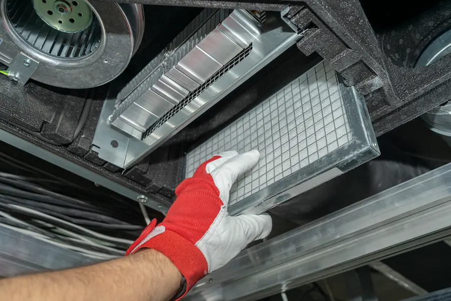 A hand checking the air filters from a duct, performing a duct cleaning.