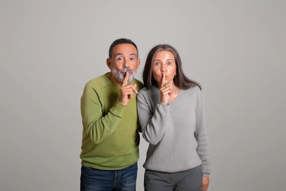 Top heat pump repair and maintenance services - Positive caucasian aged couple making shh gesture with finger, isolated on gray background