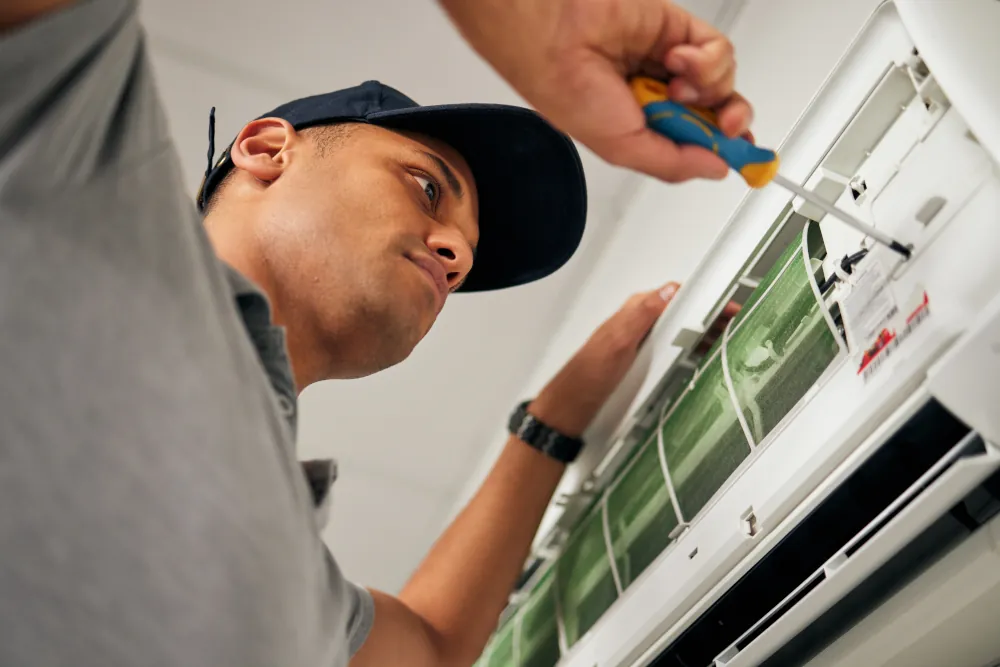 Maintenance, air conditioner and man with screwdriver for problem solving on machine from below.