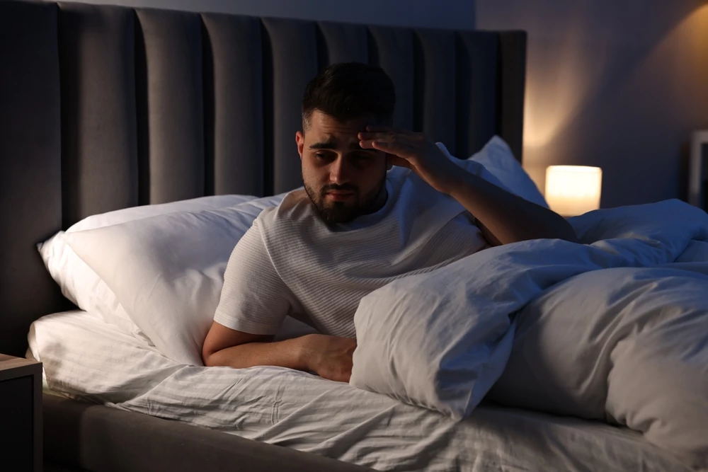 Frustrated man suffering from insomnia in bed