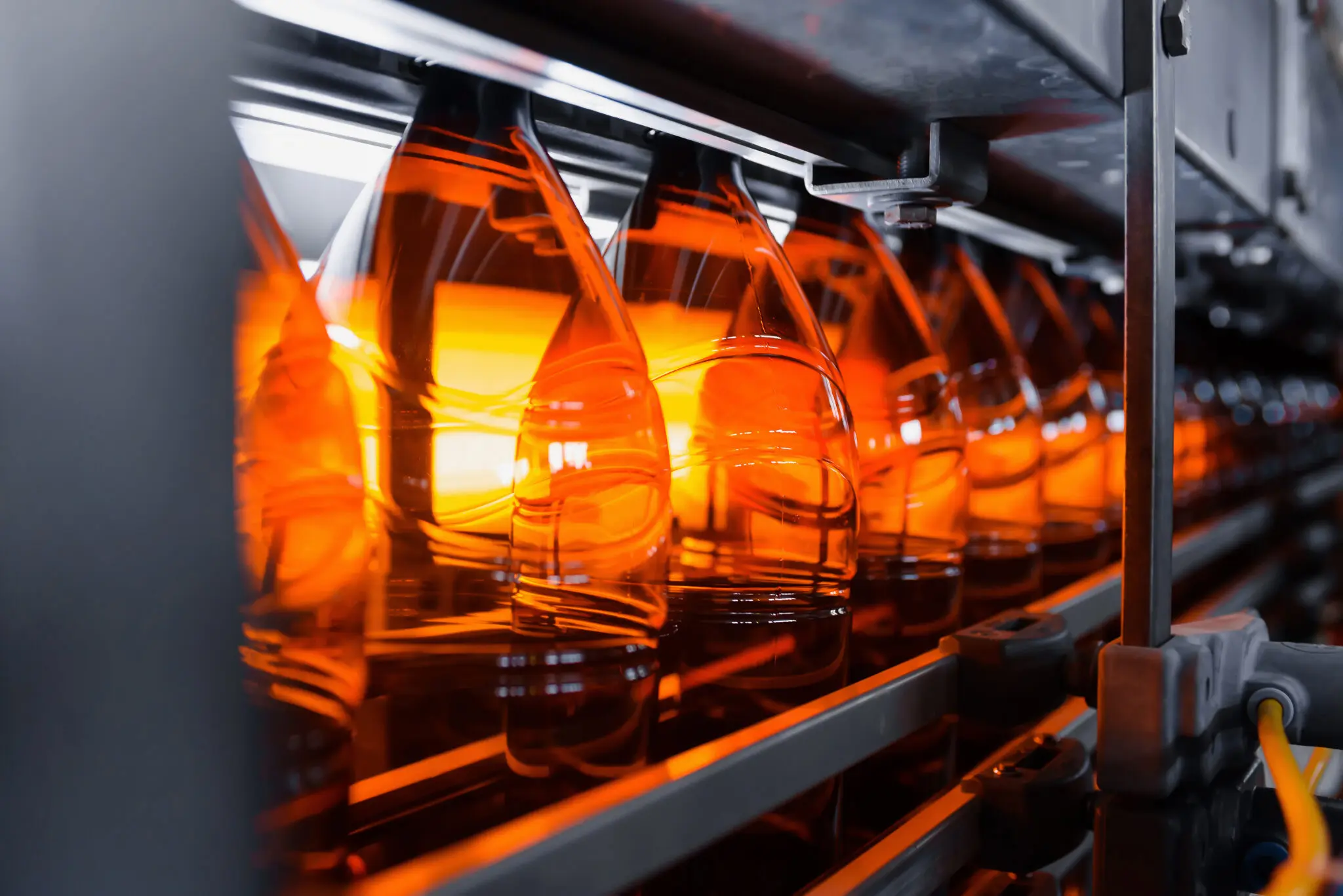 Plastic brown beer bottles on a conveyor belt close-up. Production of plastic bottles. | Sly Air Pollution Control Plastic brown beer bottles on a conveyor belt close-up. Production of plastic bottles.
